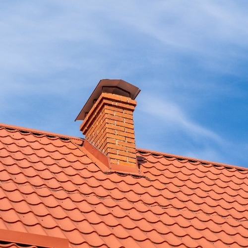 brick chimney on top of a red tile roofing system